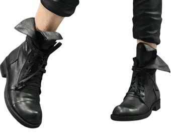 May include: Black leather ankle boots with a lace-up design and folded-over tops. The boots have a rounded toe and a low heel. The image shows the boots from two different angles, highlighting their details and style.