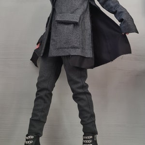 K&ouml;nnte beinhalten: Ein anthrazitfarbener Blazer mit geschlitztem Seitenteil und schwarzem Innenfutter, kombiniert mit einer passenden anthrazitfarbenen, schmal zulaufenden Hose und schwarzen Stiefeletten mit silbernen Ketten und Profilsohle &uuml;ber einem wei&szlig;en Oberteil.