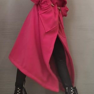 K&ouml;nnte beinhalten: Ein leuchtend pinkfarbener langer Mantel mit breitem Kragen, strukturierten Schultern und gro&szlig;en aufgesetzten Taschen. Der Mantel wird mit einer schwarzen Leggings und schwarzen Schn&uuml;rstiefeletten aus Leder mit silberfarbenen Details kombiniert.