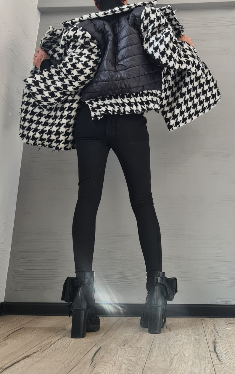 May include: A black and white houndstooth jacket with a black quilted back panel, paired with solid black leggings and black leather ankle boots featuring a block heel and a small attached pouch detail on the outer side of each boot.