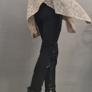 May include: A sleeveless beige knit top with a high collar, paired with black fitted trousers featuring side zippers and black leather-look ankle boots with thick block heels, multiple straps, and silver-toned metal buckles and side zippers.