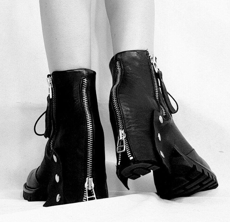 May include: A pair of black leather boots with zipper detailing on the back and sides. The boots have a chunky heel and a rounded toe.