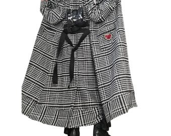 May include: A long black and white plaid coat featuring a black buckled strap at the waist, a black sequined patch on the upper back, and a red heart-shaped embellishment on the right side. The coat has long sleeves and a flared hemline.