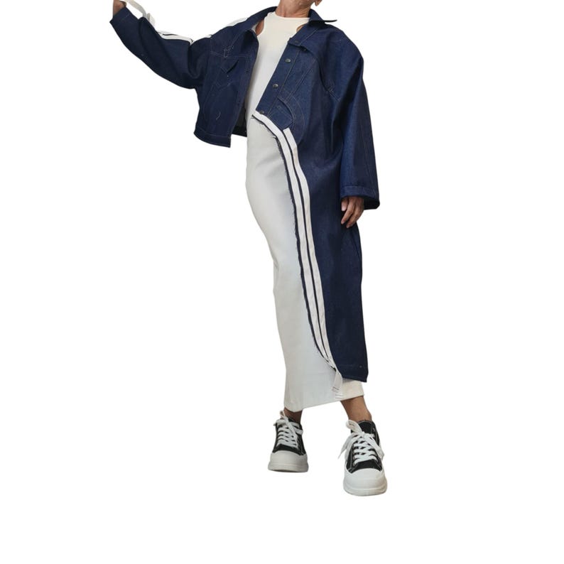 May include: A dark blue denim jacket with white stripes on the sleeves and a matching white stripe down the side of a white dress. The outfit is paired with black and white sneakers.