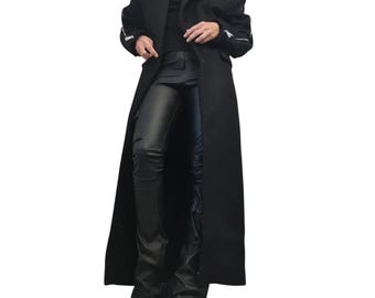 May include: A long black coat with wide lapels and silver-toned zippers on the sleeves, worn over a black top and black leather-look trousers. The ensemble is completed with black footwear, creating a monochromatic appearance in dark tones.