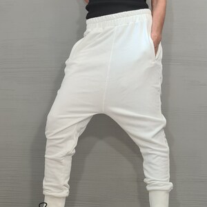 Op de afbeelding: Een zwart geribbeld tanktop met witte bies en een witte broek met lage kruis. De outfit wordt gecombineerd met witte en zwarte sneakers. De kleding is casual en comfortabel, geschikt voor dagelijks gebruik.