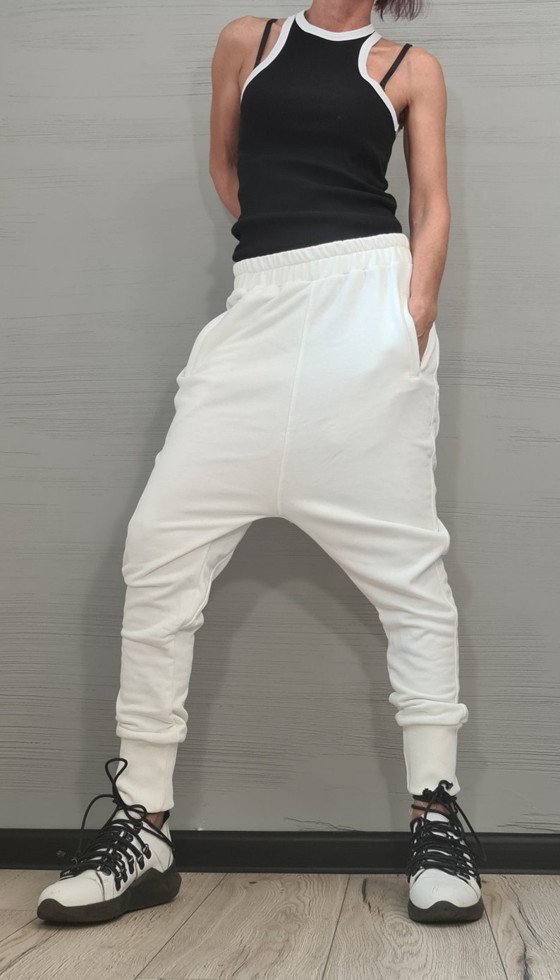 Op de afbeelding: Een zwart geribbeld tanktop met witte bies en een witte broek met lage kruis. De outfit wordt gecombineerd met witte en zwarte sneakers. De kleding is casual en comfortabel, geschikt voor dagelijks gebruik.