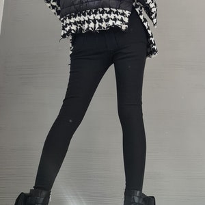 May include: A jacket featuring a black quilted center panel and black and white houndstooth patterned sleeves and collar, paired with solid black fitted trousers and black leather ankle boots with block heels and side pocket details.