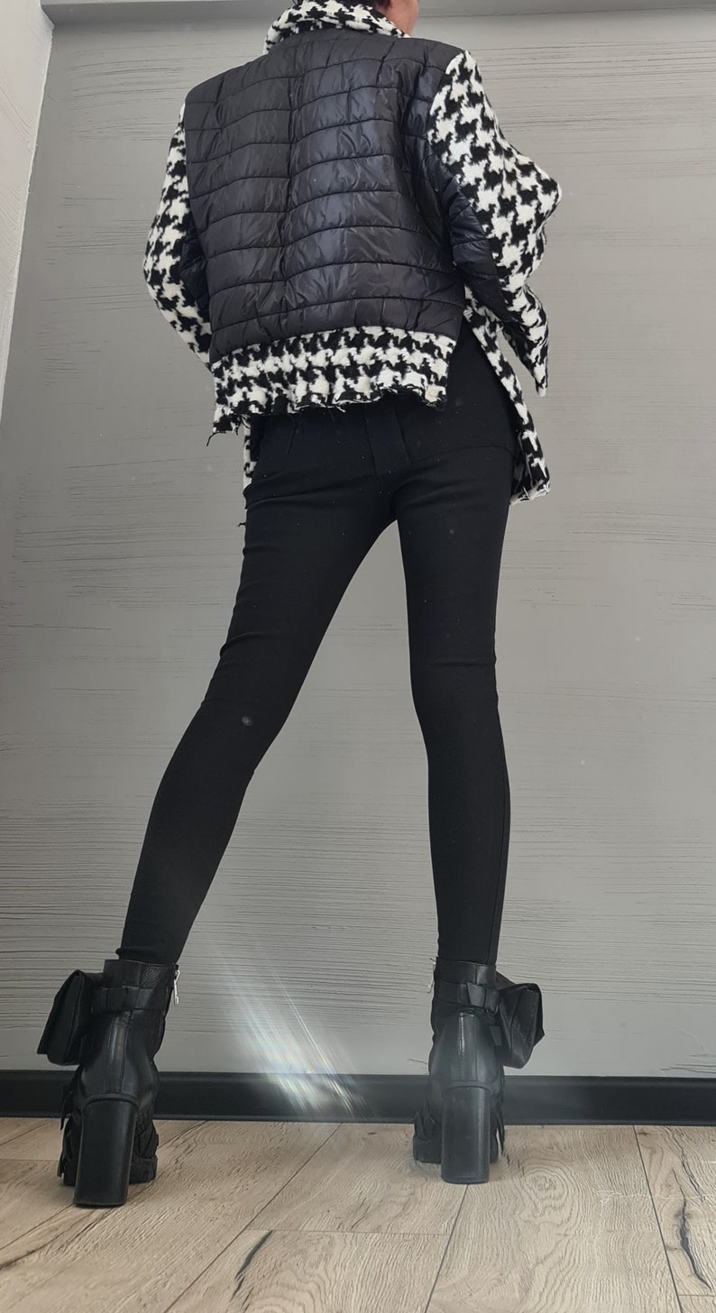 May include: A jacket featuring a black quilted center panel and black and white houndstooth patterned sleeves and collar, paired with solid black fitted trousers and black leather ankle boots with block heels and side pocket details.