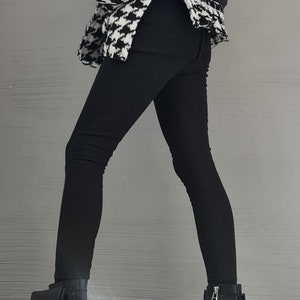 May include: A black and white houndstooth patterned jacket with a black quilted back panel, paired with solid black leggings and black leather ankle boots featuring a block heel, a side zipper, and a small attached pouch on the outer ankle.