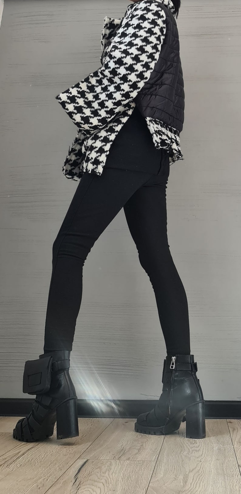 May include: A black and white houndstooth patterned jacket with a black quilted back panel, paired with solid black leggings and black leather ankle boots featuring a block heel, a side zipper, and a small attached pouch on the outer ankle.