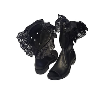 Könnte beinhalten: Schwarze Leder-Peep-Toe-Stiefel mit Reißverschluss und dekorativer schwarzer Spitzentrimmung am oberen Rand. Die Stiefel haben einen niedrigen Absatz und ein einzigartiges, gothisch inspiriertes Design.