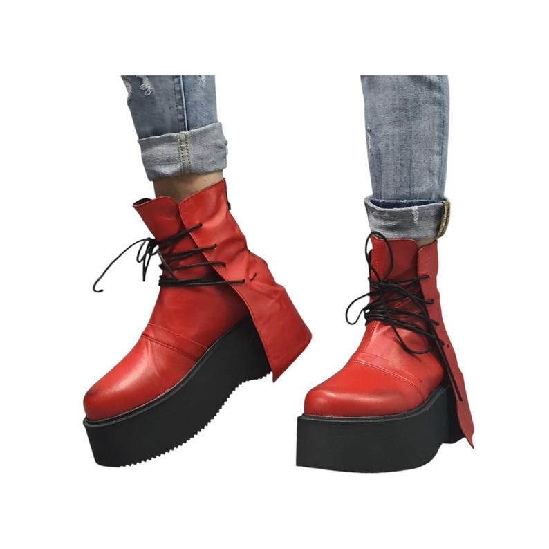 K&ouml;nnte beinhalten: Rote Plateau-Stiefel mit schwarzen Sohlen und Schn&uuml;rsenkeln. Die Stiefel haben ein einzigartiges Design mit einem seitlichen Klappverschluss und werden mit blauen Jeans getragen. Die Plattformh&ouml;he betr&auml;gt ca. 5 cm.