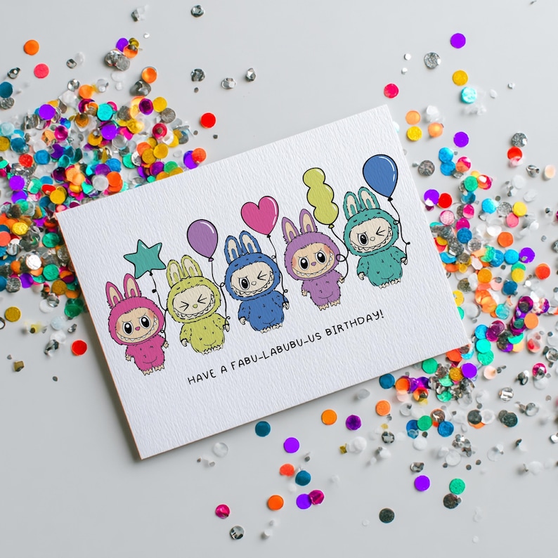 May include: A white greeting card with a colorful illustration of six cartoon characters in bunny costumes, each holding a balloon. The card reads "HAVE A FABU-LABUBU-US BIRTHDAY!" and is surrounded by colorful confetti.