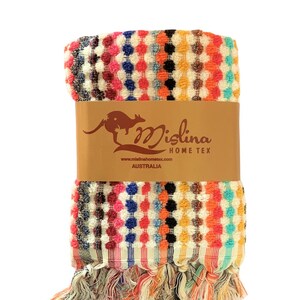 May include: A colorful, patterned towel with a textured design. The towel features a repeating pattern of dots in various colors, including pink, blue, orange, and black. The towel is wrapped with a brown paper band that has a kangaroo logo and the text "Mislina Home Tex Australia."