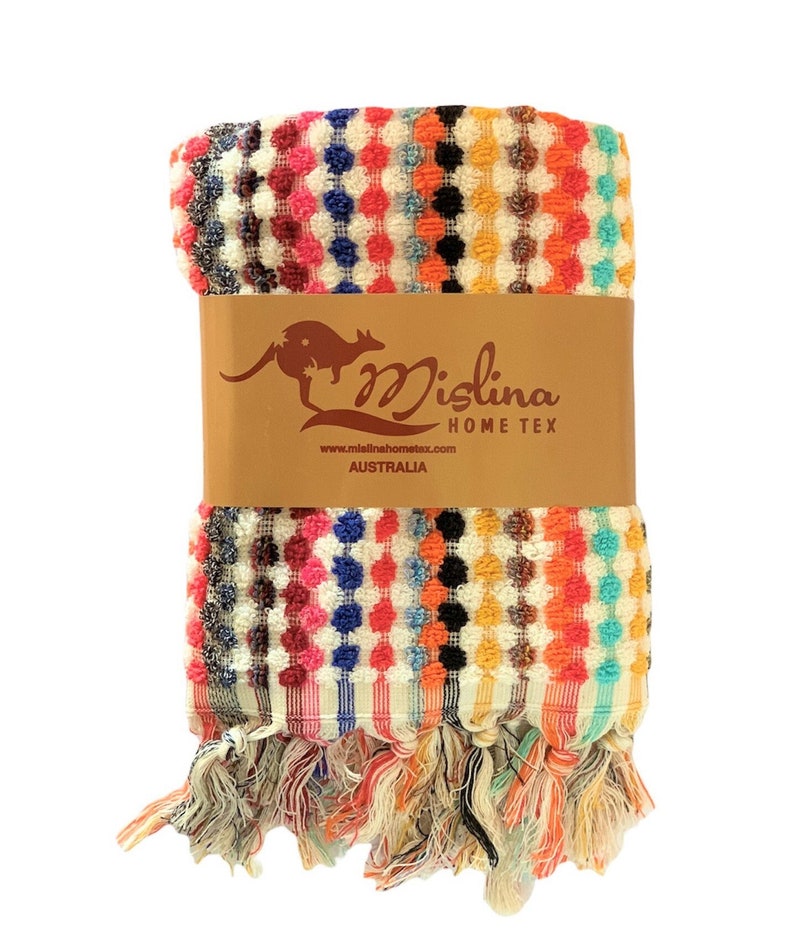 May include: A colorful, patterned towel with a textured design. The towel features a repeating pattern of dots in various colors, including pink, blue, orange, and black. The towel is wrapped with a brown paper band that has a kangaroo logo and the text "Mislina Home Tex Australia."