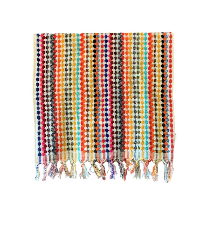 May include: A colorful striped towel with a textured dot pattern. The towel features vertical stripes in various colors, including red, orange, yellow, blue, and black. The bottom edge has decorative tassels.