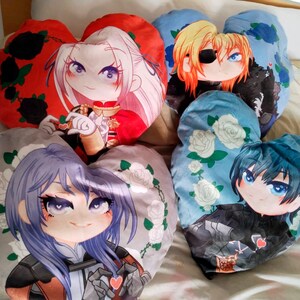 Könnte beinhalten: Vier herzförmige Plüschkissen mit verschiedenen Anime-Charakteren. Die Kissen sind rot, blau, hellblau und grau. Jedes Kissen zeigt einen anderen Charakter mit einzigartigen Designs und Details.