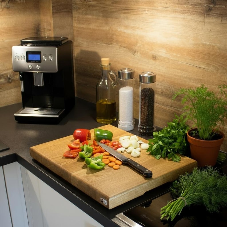 May include: A kitchen scene with a black espresso machine, a wooden cutting board with chopped vegetables, a knife, and various spices. A bottle of olive oil, salt, and pepper shakers are also present. A small potted plant and fresh herbs complete the setup.