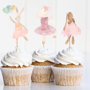 May include: Three cupcake toppers featuring watercolor illustrations of ballerina animals. A bunny holding balloons, a bunny wearing a pink tutu, and a mouse wearing a purple tutu.