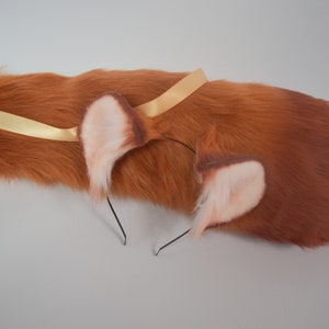 May include: A brown faux fur tail with a gold ribbon and a headband with two brown and white faux fur ears.