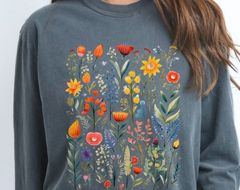 May include: A dark gray sweatshirt with a colorful floral print. The print features a variety of flowers, leaves, and stems in shades of red, orange, yellow, green, and blue.