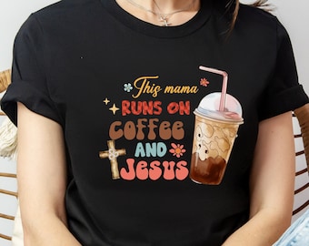 May include: Black t-shirt with a graphic design featuring a coffee cup and a cross with the text "This mama runs on coffee and Jesus".