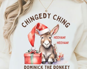 May include: White sweatshirt with a brown graphic of a donkey wearing a Santa hat and holding a red gift box. The text "Chingedy Ching Heehaw! Heehaw! Dominick the Donkey" is printed on the sweatshirt.