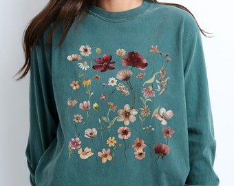May include: A teal long-sleeve shirt with a floral print featuring various shades of pink, red, and yellow flowers.