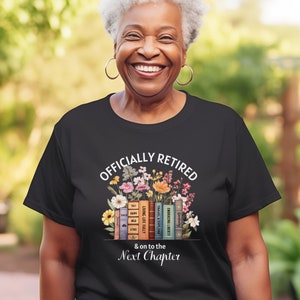 May include: Black t-shirt with white text that reads "Officially Retired & on to the Next Chapter". The text is surrounded by a floral design with a stack of books underneath.