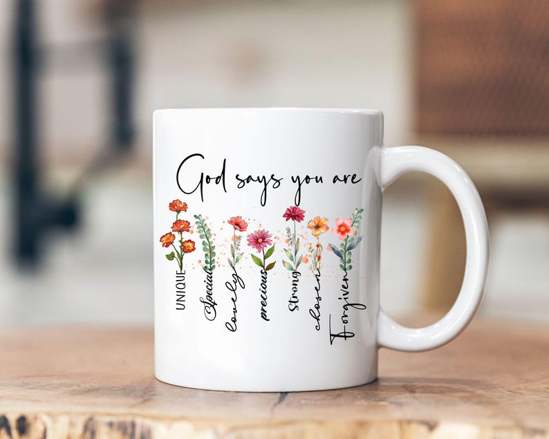 May include: White ceramic mug with a floral design and the text "God says you are" with the words "unique, special, lovely, precious, strong, chosen, forgiven" written vertically down the side.