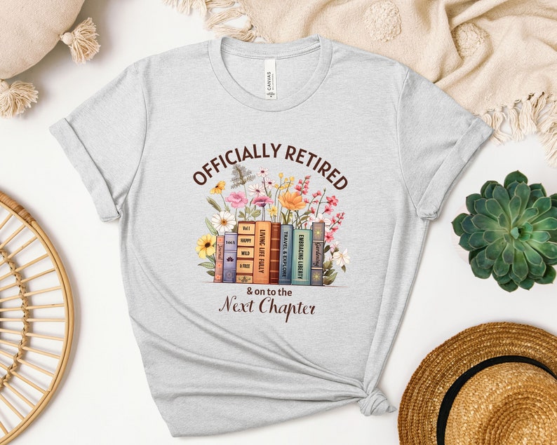May include: Gray t-shirt with the text "OFFICIALLY RETIRED & on to the Next Chapter" in brown lettering. The text is surrounded by a stack of books with floral illustrations.