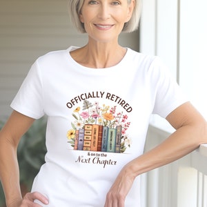 May include: White t-shirt with the text "Officially Retired & on to the Next Chapter" printed on it. The text is surrounded by a stack of books and colorful flowers.