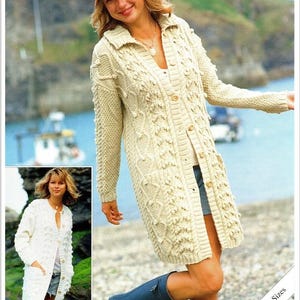 Könnte beinhalten: Ein langer, cremefarbener Strickcardigan mit einem Zopfmuster und Knopfleiste. Der Cardigan wird von einer Person mit einem braunen Hut und einer blauen Jeans getragen. Der Text "Sirdar" ist am unteren Rand des Bildes sichtbar.