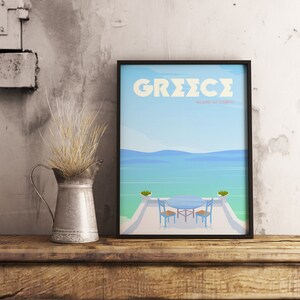 May include: A black framed poster with a blue and white illustration of a seascape with two chairs and a table on a patio. The poster has the text "GREECE ISLAND OF CORFU" in pink and white.