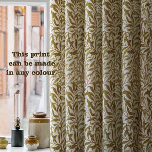 May include: Cream-colored curtains with a repeating pattern of olive green leaves and stems. The text "This print can be made in any colour" is visible. The curtains are hanging in front of a window.