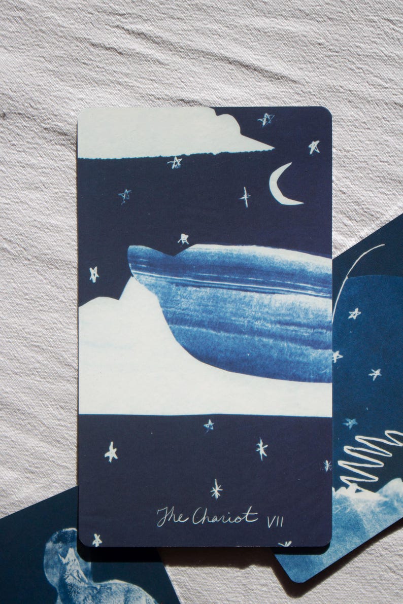 May include: A tarot card featuring a night sky scene with a crescent moon, stars, and a stylized mountain range. The card is predominantly navy blue and white, with the words "The Chariot VII" at the bottom.