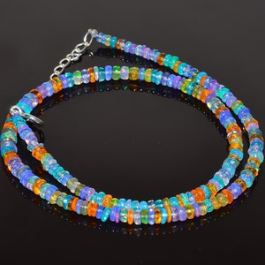 May include: A multi-strand necklace made of small, round, iridescent opal beads in shades of blue, green, orange, and purple. The necklace has a silver clasp.