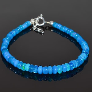May include: A blue opal beaded bracelet with a silver clasp. The beads are round and have a slight iridescent sheen.