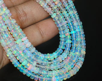 May include: Strands of iridescent opal beads. The beads are small, round, and display a range of colors including white, blue, and pink. The beads are strung together, creating a necklace or bracelet.