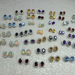 Può includere: Assortimento di orecchini a perno d'argento con varie pietre preziose, tra cui opale, topazio blu, ametista e granato.