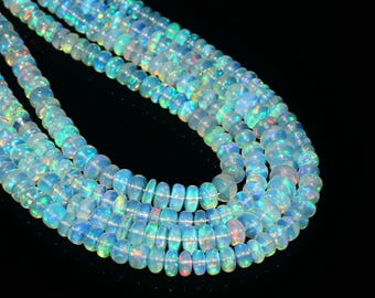 May include: Strands of iridescent opal beads. The beads are a mix of clear and milky white, with flashes of blue, green, and orange. The beads are round and smooth, and they are strung together to form necklaces.