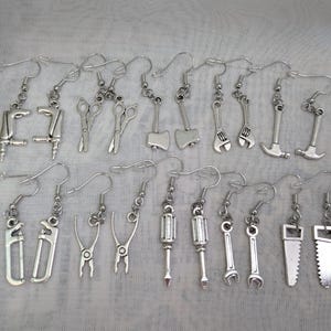 May include: A set of 20 silver-toned earrings featuring various tool designs, including wrenches, pliers, saws, and screwdrivers.