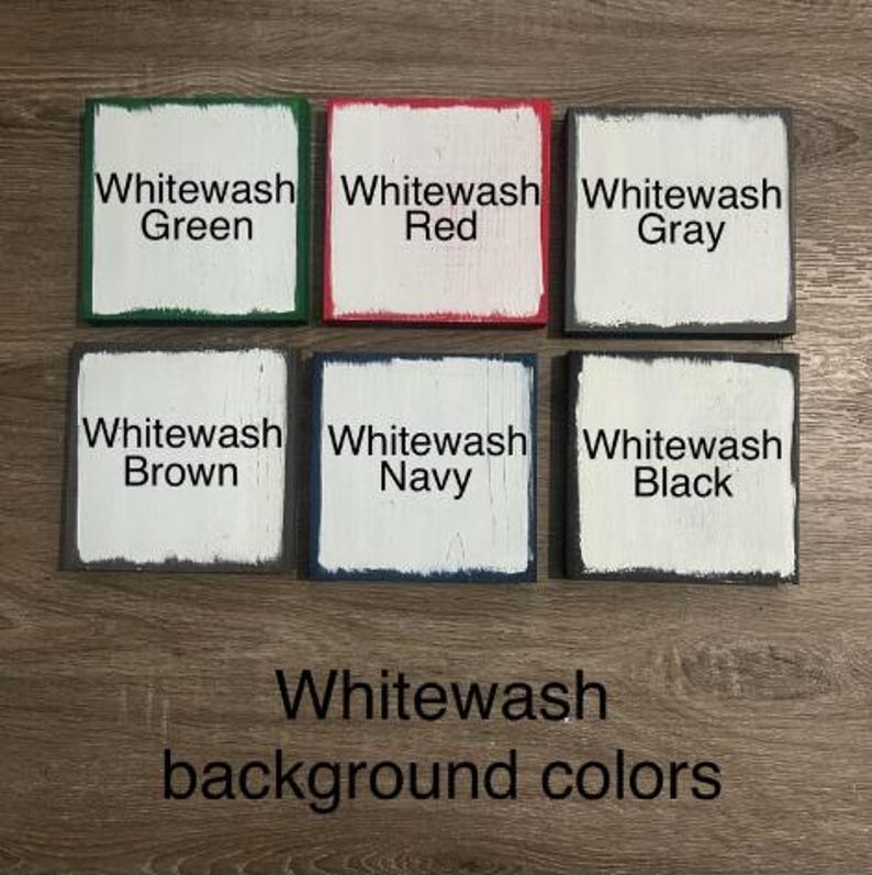 May include: Six square wooden blocks arranged in two rows, each featuring a white center with distressed edges in green, red, gray, brown, navy, and black. Each block is labeled with its corresponding color name in black text.