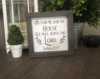 May include: A gray wooden sign with white text that reads "As for me and my house we will serve the Lord. Joshua 24:15".