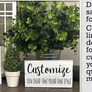 May include: White wooden signs with the word "Customize" in black script. The signs also include text for sign color, font color, and font style. The image includes greenery and a window in the background.