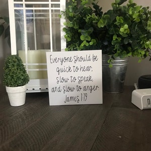May include: A white sign with black text that reads "Everyone should be quick to hear, slow to speak, and slow to anger. James 1:19".