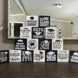 Puede incluir: Un conjunto de 14 letreros de madera en blanco y negro con texto sobre el tema de la graduación. Los letreros presentan frases como "Kiss My Class Goodbye", "The Tassel Was Worth The Hassle", "Way To Go Grad", "Senior Graduate", y "Class of 2025".