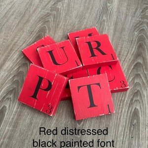 Op de afbeelding: Rode, verweerde houten tegels met zwart geschilderde letters. De letters zijn P, U, R en T. De tegels hebben een versleten, vintage uitstraling. De tekst onderaan luidt "Red distressed black painted font."
