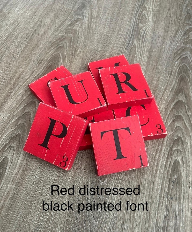 Op de afbeelding: Rode, verweerde houten tegels met zwart geschilderde letters. De letters zijn P, U, R en T. De tegels hebben een versleten, vintage uitstraling. De tekst onderaan luidt "Red distressed black painted font."
